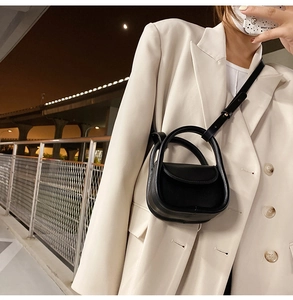 Détail du mini sac en cuir noir minimaliste avec poignée anneau porté par un mannequin