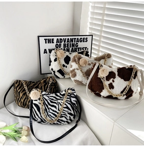 Detailed view of plush tote bags with cow and zebra patterns featuring gold chain straps