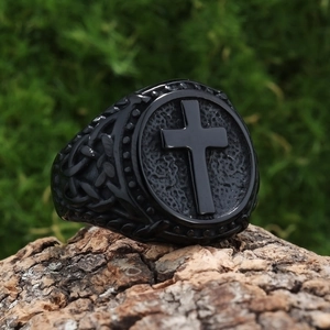 Macro detail of retro stainless steel ring with black cross relief on wood background