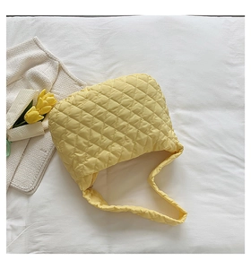 Top view of yellow quilted nylon tote bag with floral accents on white fabric