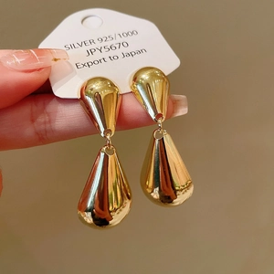 Close-up of golden teardrop earrings with high-polish finish on a Silver 925 card