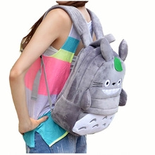 Side view of a grey plush Totoro shaped backpack with green leaf detail on a model