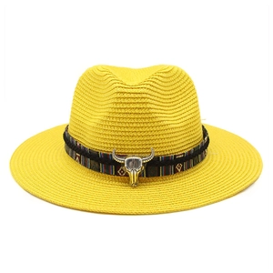 Dettaglio di un cappello di paglia giallo con fascia etnica e ciondolo a testa di toro