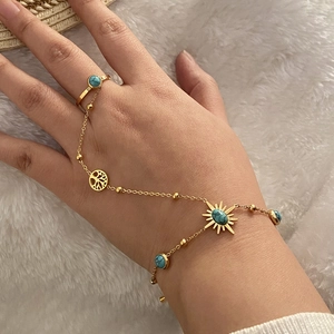 Gros plan d'un bracelet bague doré avec des pierres turquoises et des breloques soleil