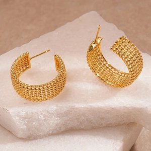 Detail of gold C-shaped earrings with intricate bead-woven texture on stone display