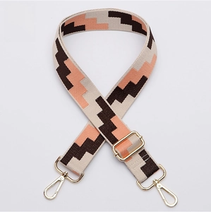 Close-up of adjustable wide woven bag strap with geometric patterns and gold metal hooks