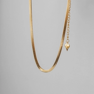 Detailed view of golden snake chain necklace with adjustable heart pendant extension