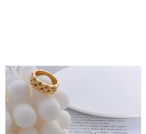 Detailed close-up of a gold ring with woven texture displayed on a white bubble ornament