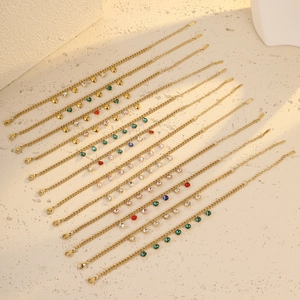 Gold stainless steel bracelets with colorful heart and teardrop gemstones on stone surface