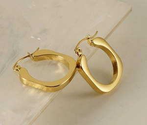 Detailed close-up of gold U-shaped earrings on a marble surface with polished finish