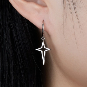 Detail showing the silver four-pointed star charm earring on a model's ear