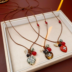 Detail of bohemian wax cord necklaces with heart-shaped natural stone and cross charms