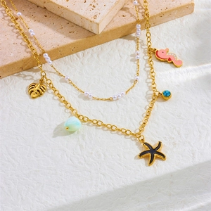 Detail of gold layered necklace featuring seahorse, leaf, starfish and pearl charms