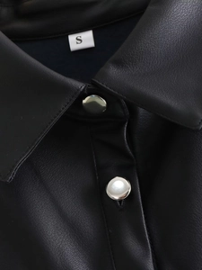 Detail shot of the black leather vest collar and polished silver metal buttons