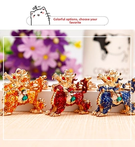 Detailed view of three enamel dragon keychains in gold, red, and blue with inset gems