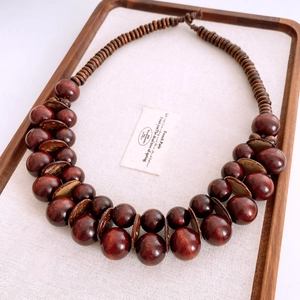 Dettaglio di grandi perle di legno rosso scuro e dischi di cocco su una collana etnica