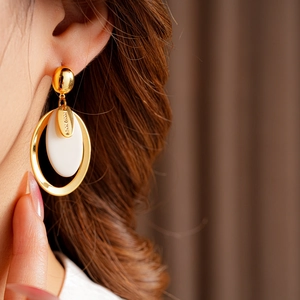 Close-up of gold plated resin oval earring with silver pin and Hand Made tag detail