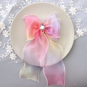 Close-up of pink and green gradient ribbon bow hair clip with teardrop rhinestone