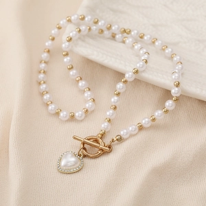 Detail of beaded pearl necklace with gold OT toggle clasp and crystal heart pendant