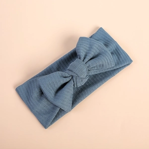 Close-up of blue-grey ribbed knit bow headband for babies on a beige background