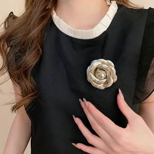 Detailed close-up of a vintage champagne gold rose brooch on a black dress lapel
