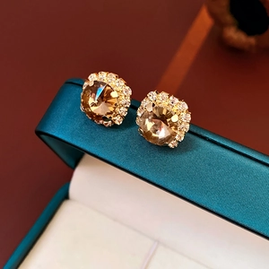 Close-up of luxury gold round stud earrings with champagne center stones and micro-pave diamonds