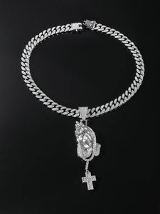 Detailed view of hip hop silver Cuban chain with iced out praying hands and cross pendant