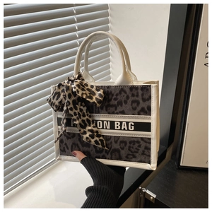 Close-up of leopard print tote bag featuring a bow and 'FASHION BAG' ribbon detail