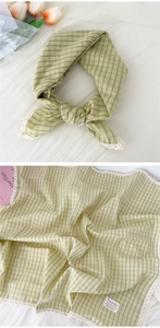 Close-up of yellow and purple plaid square scarf featuring white lace edges and linen texture