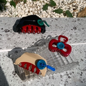 Detailed shot of bow-shaped hair claws with colorful buttons and elastic cord accents