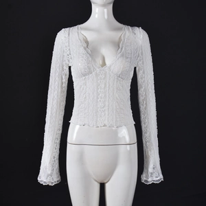 Detailed close-up of white lace long sleeve top with deep V-neck and flared cuffs