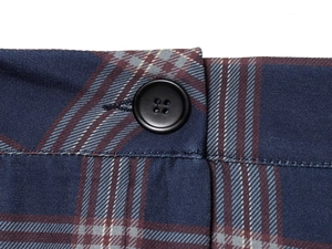 Close-up of blue and red plaid fabric with a matte black button and woven texture detail