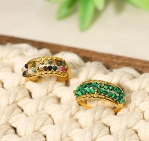 Macro detail of gold beaded rings featuring colorful malachite and natural tourmaline stones