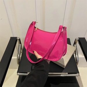 Glossy pink patent leather underarm shoulder bag with golden zipper on a chair