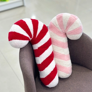 Close-up of candy cane shaped Christmas pillows in red, pink, and white plush fabric