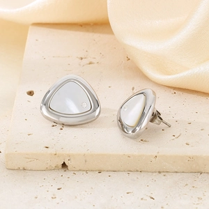 Close-up of triangle stud earrings with white shell inlay and zircon on stone texture