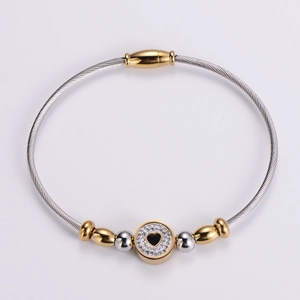 Detail of two-tone braided wire bracelet featuring heart motif and magnetic clasp