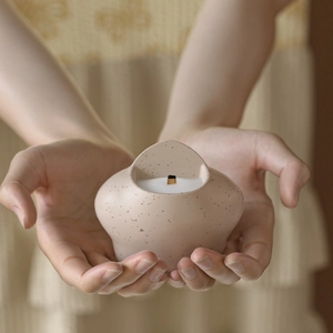 Pink speckled ceramic aromatherapy candle with wood wick held in hand for home decor