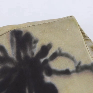 Close-up of olive green satin dress with black floral print and fine stitching detail