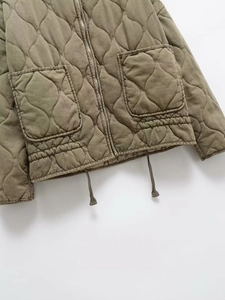 Detail of army green quilted jacket featuring diamond pattern, large pockets and drawstring hem