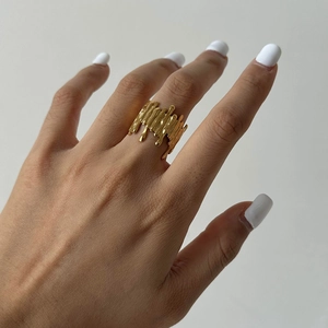 Detail of a wide gold lava-textured irregular ring worn on hand with liquid metal finish