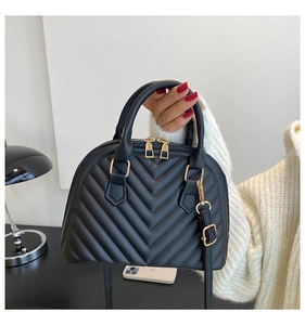 Detail of black chevron quilted shell bag with gold zippers and adjustable shoulder strap