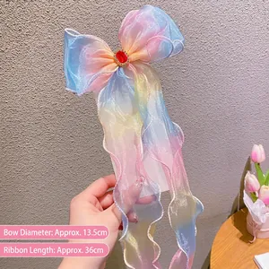 Detail of gradient rainbow organza hair bow with a red gem and long flowing ribbons