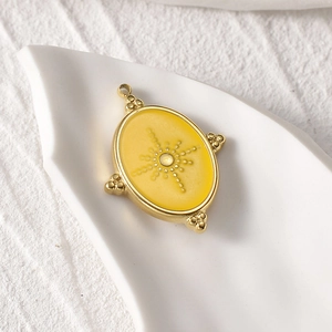 Detailed view of the 14k gold plated oval pendant featuring sunburst engraving