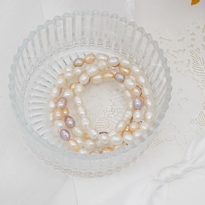 Macro shot of colorful freshwater pearls in a glass bowl on white lace fabric