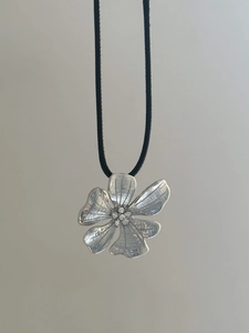 Detailed macro view of 18k gold plated flower pendant with zircons on black cord necklace