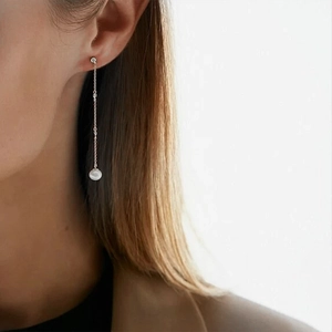 Close-up of S925 silver chain earrings with dangling white pearl on model's ear