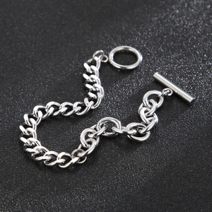Bracelet gourmette argenté avec fermoir à bascule OT sur une surface texturée