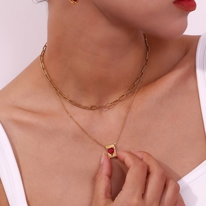 Close-up of gold double-layer necklace with a red heart pendant on female model neck