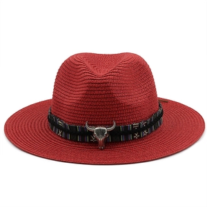 Detail of red straw fedora with ethnic woven band and silver bull head decoration